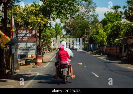 BALI, INDONESIEN - 01. Dezember 2019: Traditionelles balinesisches Stammdorf. Autos und Motorräder fahren auf der Straße in Bali, Indonesien Stockfoto