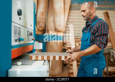 Zimmerer arbeitet auf Holzbearbeitungsmaschine, Holzbau, Zimmerei. Die Holzbearbeitung auf der Möbelfabrik, die Produktion der Erzeugnisse der natürlichen Materialien Stockfoto