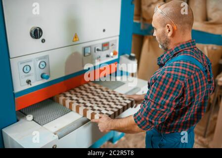 Zimmerer arbeitet auf Holzbearbeitungsmaschine, Holzbau, Zimmerei. Die Holzbearbeitung auf der Möbelfabrik, die Produktion der Erzeugnisse der natürlichen Materialien Stockfoto