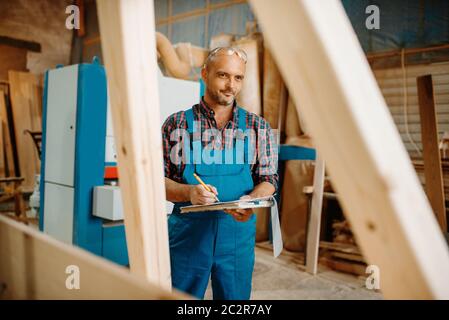 Tischler mit Notizbuch, Holzbearbeitung, Holzbau, Zimmerei. Die Holzbearbeitung auf der Möbelfabrik, die Produktion der Erzeugnisse der natürlichen Materialien Stockfoto