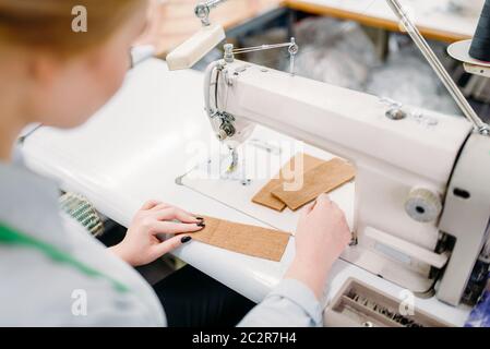 Schneiderin näht Stoffen auf einer Nähmaschine. Tailoring oder Schneidern auf Kleidung Fabrik, Handarbeit, weibliche Näherin in Werkstatt Stockfoto