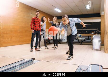 Männliche Bowler wirft Ball auf Lane. Kegelbahn Mannschaften das Spiel in Club, aktive Freizeit Stockfoto