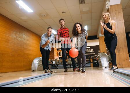 Männliche Bowler wirft Ball auf Lane, Vorderansicht, werfen in Aktion. Kegelbahn Mannschaften das Spiel in Club Stockfoto