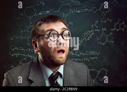 Bizarre Professor in Brille über chemische Formeln auf Tafel denken Stockfoto