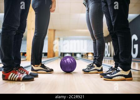 Kegelbahn Team, die Füße der Spieler im Haus Schuhe und Ball auf Lane. Freunde das Spiel in Club, aktive Freizeit Stockfoto