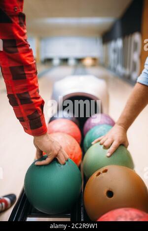 Zwei männliche Bowlers bringt Bälle vom Schrägförderer. Kegelbahn Spieler bereitet sich auf einen werfen. Klassische tenpin Spiel im Club, aktive Freizeit Stockfoto