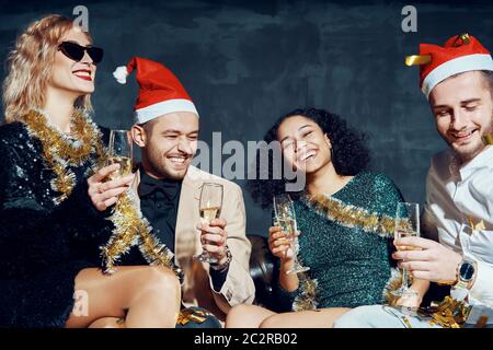 Eine Gruppe von fröhlichen Freunden feiern gemeinsam das neue Jahr, haben Spaß und trinken Champagner Stockfoto