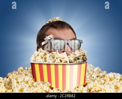 Mann in Gläsern in einem Eimer Popcorn gegen Blau