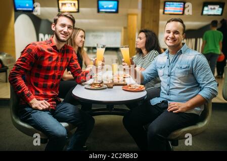 Freunde getränke Saft und isst Pizza in Bowling Club, aktive Freizeitgestaltung, gesunde Lebensweise, bowling spiel Stockfoto