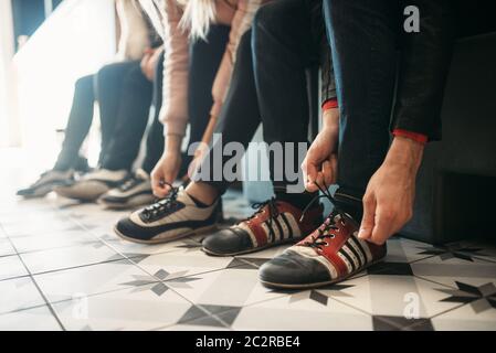 Kegelbahn Spieler Bindungen Schnürsenkel auf Haus Schuhe. Bowlers auf der Bank sitzen und bereitet sich auf den Wettbewerb im Club, aktiv Sport. Schüssel Sport Stockfoto