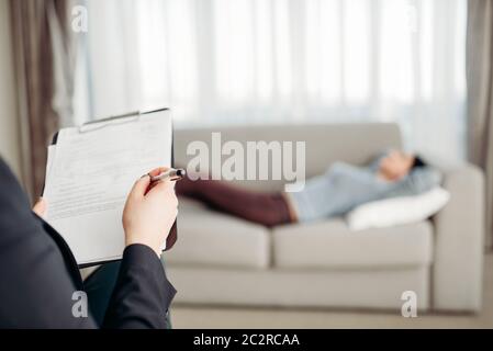 Weibliche Patient liegt auf Sofa bei psychotherapeut Rezeption. Ärztin schreibt Notizen in Notepad, professionelle Psychologie Unterstützung Stockfoto