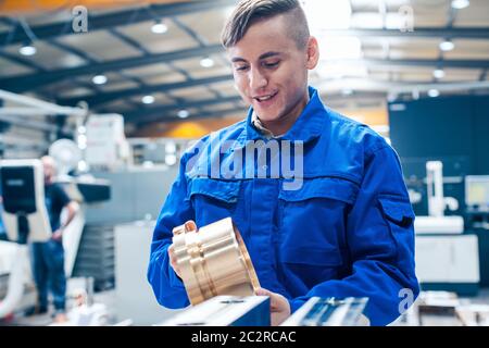 Lehrling in der Metallbearbeitung, der sich anschaut, dass das Werkstück zufrieden ist Stockfoto