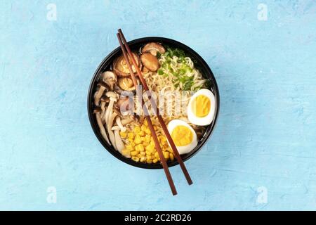 Ramen. Soba Nudeln mit gekochten Eiern, Shiitake-pilze, und Gemüse, schossen ausdem oben auf blauem Hintergrund mit Stäbchen Stockfoto