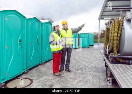 Arbeiter, die die mobile Toilette vor der Auslieferung an den Kunden inspizieren Stockfoto