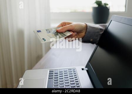 Hand Geld von Laptop geben. Online arbeiten von zu Hause aus Konzept Stockfoto