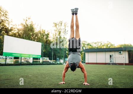 Männlicher Athlet, der auf den Händen auf dem Kopf steht, Outdoor-Fitness-Workout. Starker Sportler im Park Stockfoto