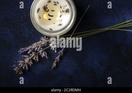 Eine brennende Kerze mit Lavendel-Duft, Nahaufnahme von oben nach unten auf dunklem Hintergrund mit Copyspace. Zero Waste Weihnachtskonzept, a h Stockfoto