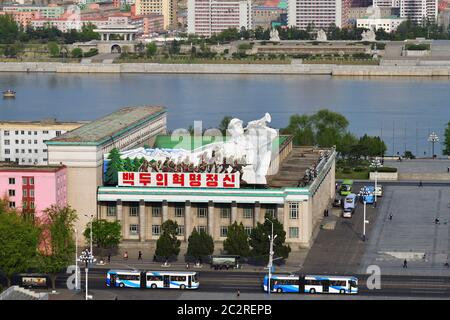 Pjöngjang, Nordkorea - 29. April 2019: Die Ecke des zentralen Platzes von Kim Il Sung, Gebäude mit Propagandabanner und Taedong River Stockfoto