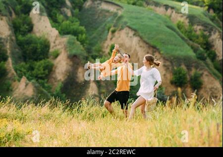 Junge Familie mit kleiner Tochter spielt, hat Spaß, läuft und lacht fröhlich. Stockfoto