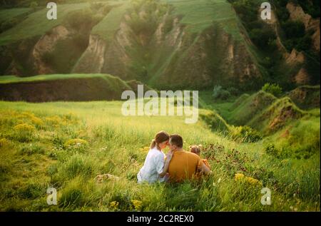 Familie mit kleiner Tochter ruht beim Wandern auf der Wiese auf Schluchten Hintergrund. Rückansicht. Stockfoto