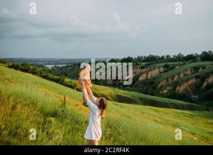 Junge Mutter hat Spaß und spielt mit seiner Tochter beim Spaziergang im Park. Stockfoto