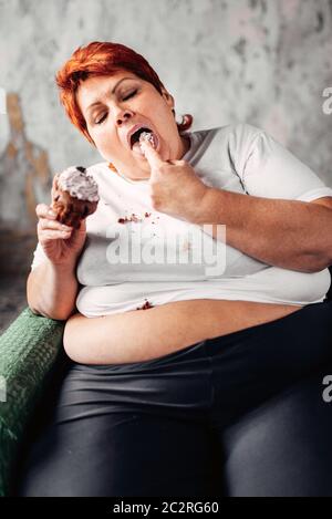 Übergewichtige Frau isst süße Kuchen, Faulheit und Übergewicht. Ungesunde Nahrung essen, Fettsäuren Weiblich Stockfoto