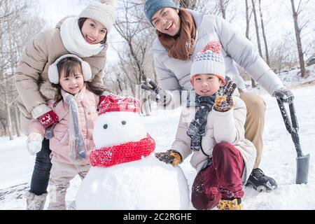 Glückliche Familie machen einen Schneemann im Schnee Stockfoto
