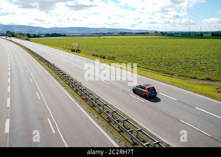 Heidelberg, Deutschland. Juni 2020. Ein Auto fährt vor einem Feld im Gaulschlag-Gebiet, einem der beiden möglichen Standorte für die neue Ankunftsstelle für Flüchtlinge, an der Bundesstraße 535. Auf dem Gelände des bestehenden Ankunftszentrums in der ehemaligen US-Siedlung Patrick-Henry-Village soll ein neuer Stadtteil entstehen. Das Ankunftszentrum soll daher an einen anderen Standort umziehen. Quelle: Uwe Anspach/dpa/Alamy Live News Stockfoto