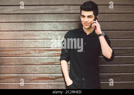 Portrait-Modell jung gutaussehend vermuten Männer, dass die türkische mittlere östliche Brunette in schwarzem Hemd Handtelefon verwendet, um Technologie anzurufen Stockfoto