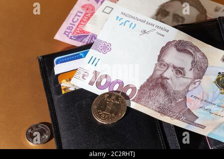 Geldbörse aus schwarzem Leder mit Geld. 1000 Hryven Banknote Nahaufnahme. Stockfoto