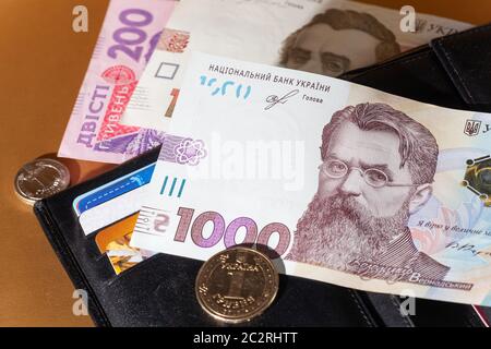 Geldbörse aus schwarzem Leder mit Geld. 1000 Hryven Banknote Nahaufnahme. Stockfoto