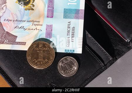 Geldbörse aus schwarzem Leder mit Geld. 1000 Hryven Banknote Nahaufnahme. Stockfoto