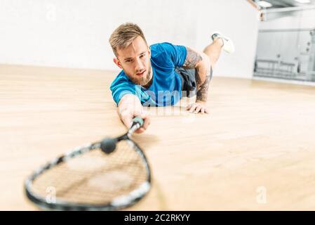 Squash-Training, männliche Spieler mit Schläger auf dem Boden liegt. Aktiv Sport Training. Spiel mit Ball und Schläger Stockfoto