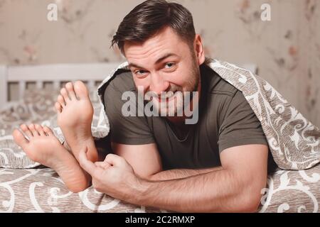 Verspielter Mann versucht, die Füße der Frau im Bett kitzeln. Stockfoto