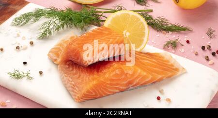 Scheiben Lachs mit Zitrone und Dill, Panorama, Nahaufnahme mit Salz und Pfeffer kochen Fisch, auf einem rosa Hintergrund Stockfoto