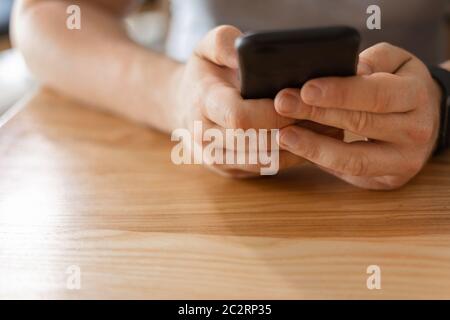 Mann Hände mit Telefon auf Holzhintergrund. 5g, virtuelles Leben, Online-Arbeit und Bildung. Stockfoto