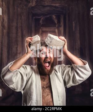 Starke Karateka bricht ein Ziegelstein auf den Kopf im Tempel Stockfoto