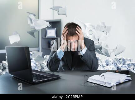 Frustrierter Geschäftsmann, der seinen Kopf hält, sitzt im Büro Stockfoto