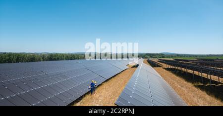 Großes Photovoltaikkraftwerk mit Menschen, die an den Tafeln stehen Stockfoto