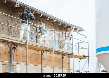 Gipser auf Gerüst auf der Baustelle mit Blick in die Kamera Stockfoto