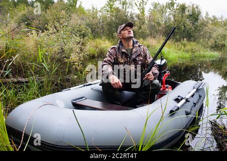 Hunter sitzt in einem Motorboot Stockfoto