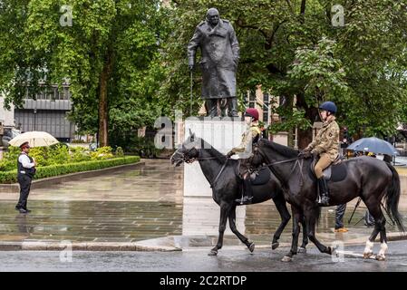 Westminster, London, Großbritannien. Juni 2020. Die Statue von Winston Churchill vor dem Palast von Westminster wurde aufgedeckt, nachdem sie durch die Maßnahmen verhindert wurde, dass sie während der Proteste von Black Lives Matter weiter zerstört wird. Der französische Präsident Emmanuel Macron besucht London zum 80. Jahrestag der Appel-Rede von Charles de Gaulle, die als Ursprung des französischen Widerstands gegen die deutsche Besatzung während des Zweiten Weltkriegs gilt, so dass die Statue enthüllt wurde. Armee berittene Soldaten reiten vorbei Stockfoto