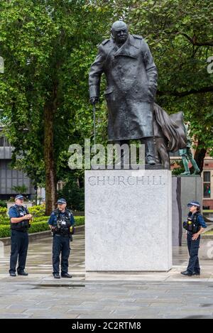 Westminster, London, Großbritannien. Juni 2020. Die Statue von Winston Churchill vor dem Palast von Westminster wurde aufgedeckt, nachdem sie durch die Maßnahmen verhindert wurde, dass sie während der Proteste von Black Lives Matter weiter zerstört wird. Der französische Präsident Emmanuel Macron besucht London zum 80. Jahrestag der Appel-Rede von Charles de Gaulle, die als Ursprung des französischen Widerstands gegen die deutsche Besatzung während des Zweiten Weltkriegs gilt, so dass die Statue enthüllt wurde. Polizeibeamte stehen Wache Stockfoto