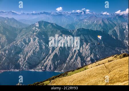 Blick auf die Alpen und ein Paragleiter über den Gardasee vom Monte Baldo, Lombardei, Italien. Stockfoto