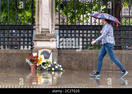 Westminster, London, Großbritannien. Juni 2020. Der Morgen ist nass geworden, als Pendler während der COVID19 Coronavirus-Pandemiesperre ihren Weg zur Arbeit finden. Einige passieren das Denkmal für PC Keith Palmer, das Blumen hat, Ehrungen daneben gelegt Stockfoto