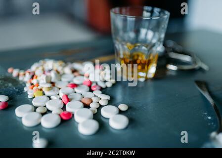 Junkie Kit, Betäubungsmittel Konzept, sucht Problem. Die Pillen sind auf Holztisch, Alkohol und Handschellen ausgelegt Stockfoto