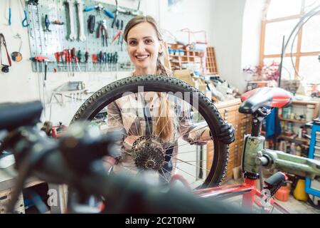 Sehr glücklich Fahrradmechaniker Frau durch das Rad Fahrrad suchen Stockfoto