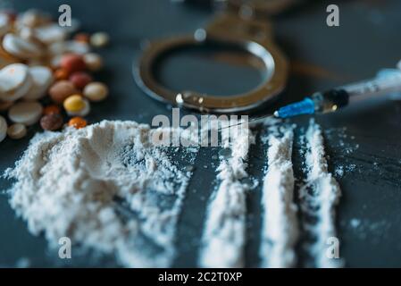 Druggy Kit, Dosis im Spoon, sucht problem Konzept. Pillen sind auf den Tisch gelegt, die Spritze für Dosis, Alkohol und Handschellen Stockfoto