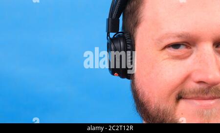 Bärtig lustig niedlich fetten Mann in einem rosa T-Shirt hört Musik und tanzt auf einem blauen Hintergrund, close-up, Copy Space. Stockfoto