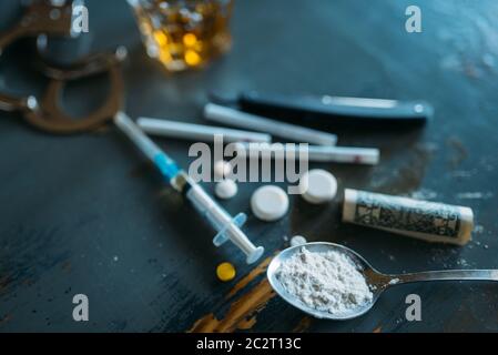 Druggy Kit, Dosis im Spoon, sucht problem Konzept. Pillen sind auf den Tisch gelegt, die Spritze für Dosis, Alkohol und Handschellen Stockfoto